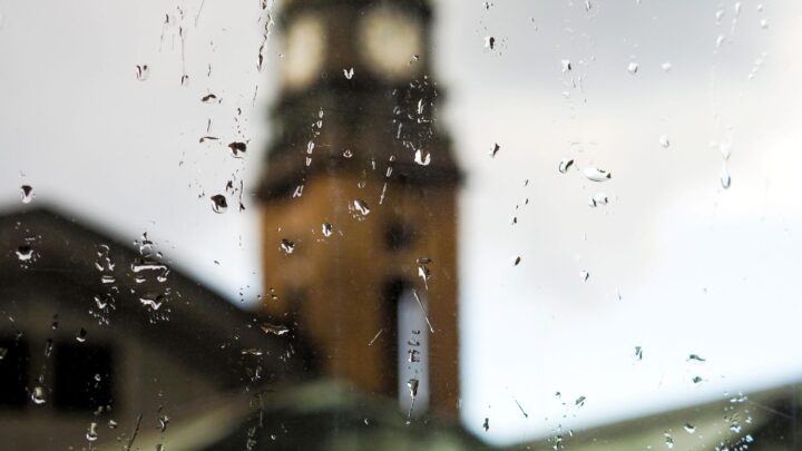 Blick durch regennasses Fenster auf den Hamburger Michel – typisches Wetter, das eine Terrassenüberdachung in Hamburg sinnvoll macht