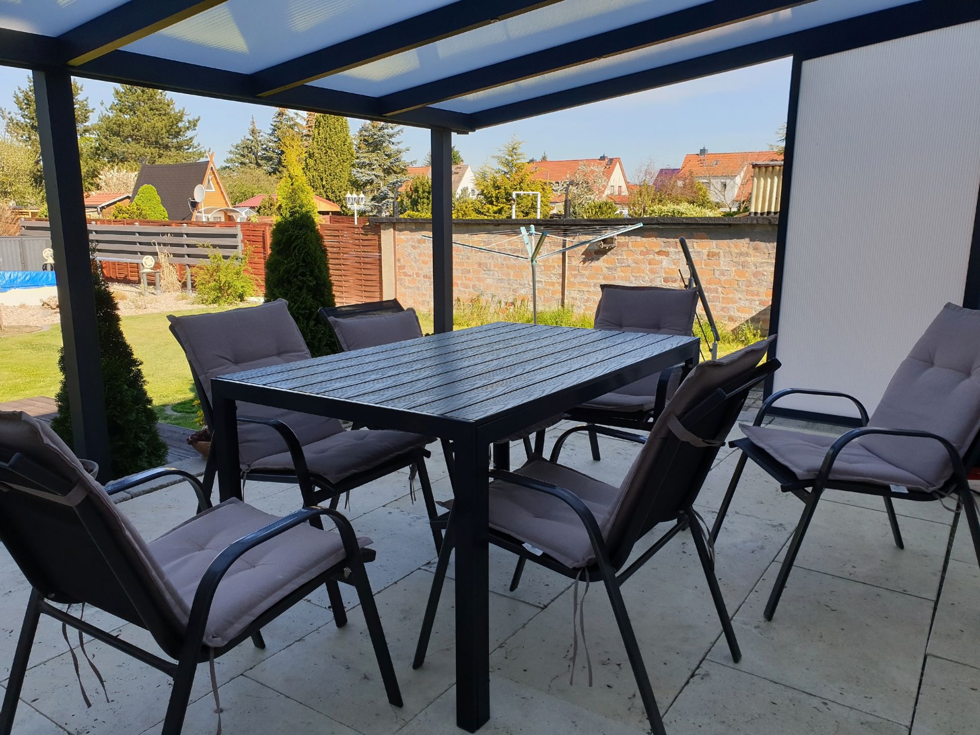 Überdachte Terrasse mit Tisch und Stühlen in einem Hamburger Garten – Terrassenüberdachung sorgt für Schutz und Komfort