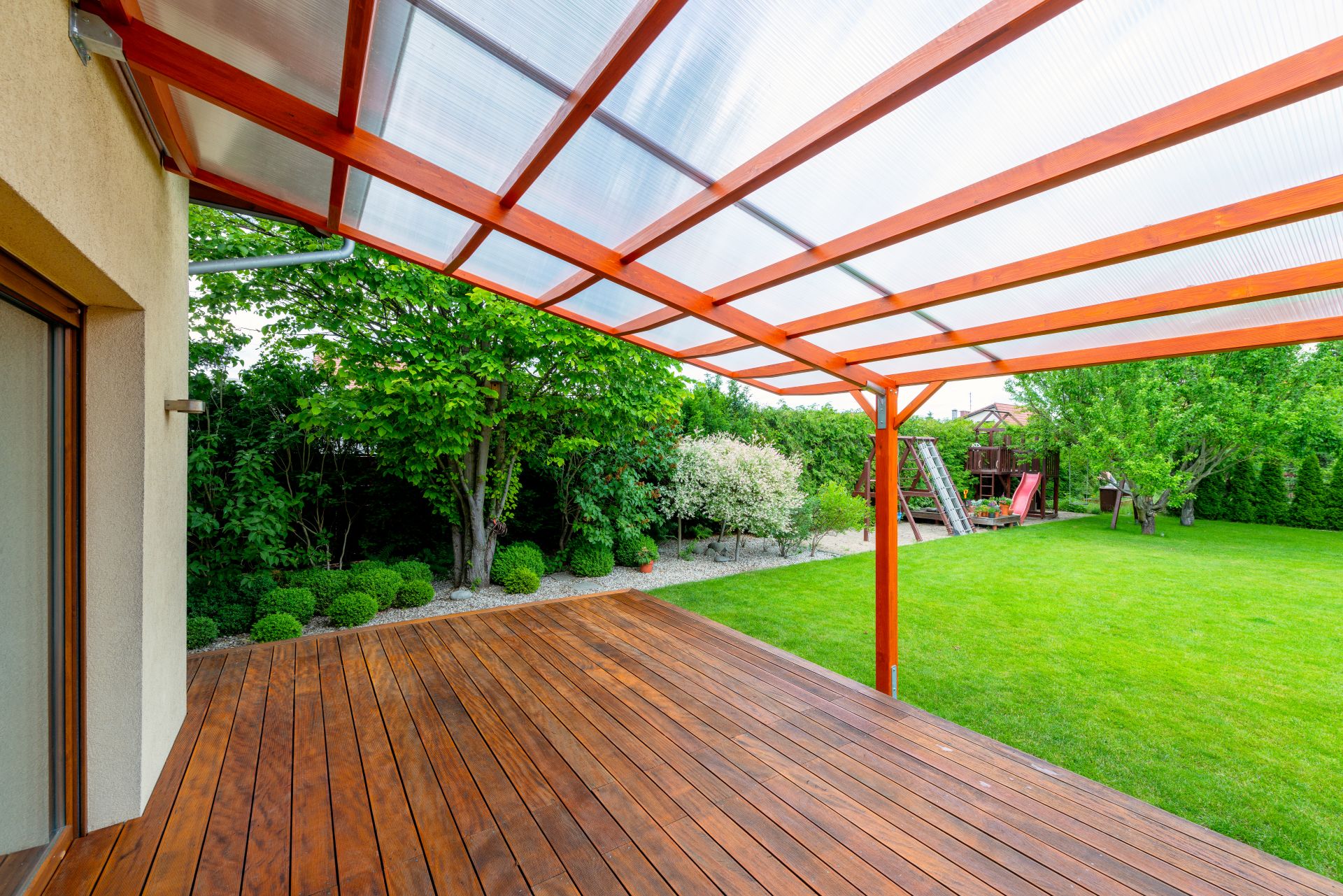 Holzterrasse mit transparenter Überdachung in Hamburg – wetterfester Schutz bei gleichzeitig offenem Gartenblick
